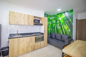 Una cocina compacta con armarios de madera, un microondas integrado y una estufa a gas.