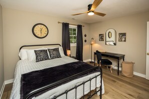 A bedroom with a bed, a desk, a chair, a ceiling fan, a window with curtains, and a wall clock. - The Julia House - Peaceful, Cozy Getaway Near Downtown Franklin (Franklin)