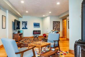 A living room with a chessboard, a television, and artwork on the walls. - Sundown Cliffs- Premium Coastal Getaway with Breathtaking Ocean Views & Sunsets (Cloverdale)
