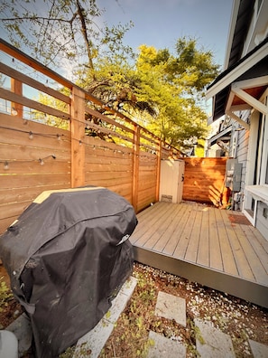 A wooden deck with a barbecue grill, surrounded by a wooden fence and trees. - Contemporary Modern Seattle Home (Seattle)