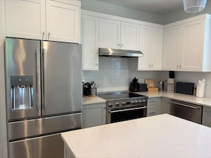 A modern kitchen with stainless steel appliances, white cabinetry, and a marble countertop. - Contemporary Modern Seattle Home (Seattle)