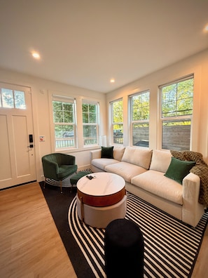 A modern living room with a white sofa, green armchair, and a round coffee table. - Contemporary Modern Seattle Home (Seattle)