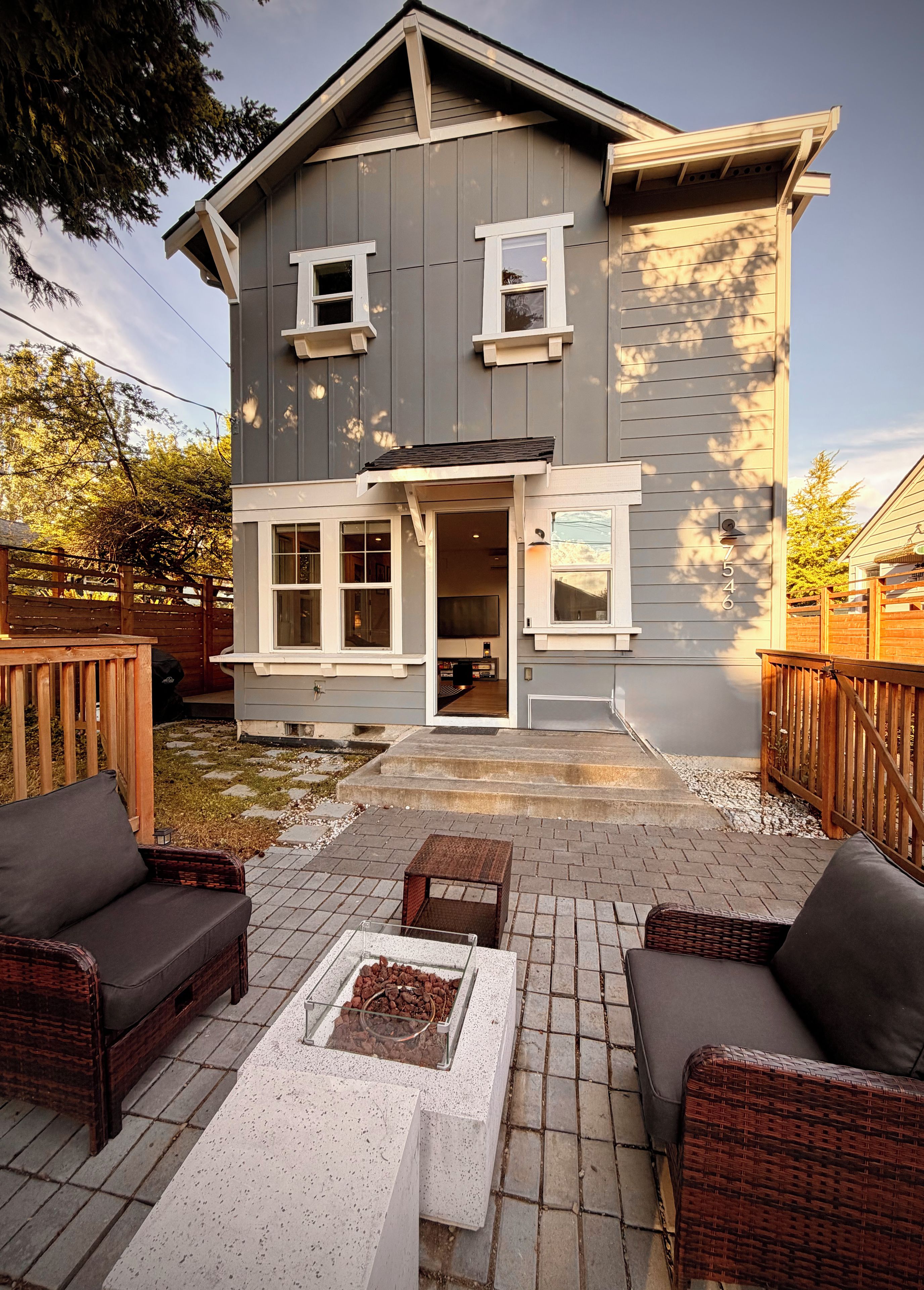 A two-story house with a front porch, a covered patio area with outdoor furniture, and a mailbox.