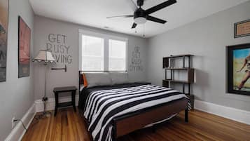 A bedroom with a bed, a ceiling fan, a window, and a bookshelf.