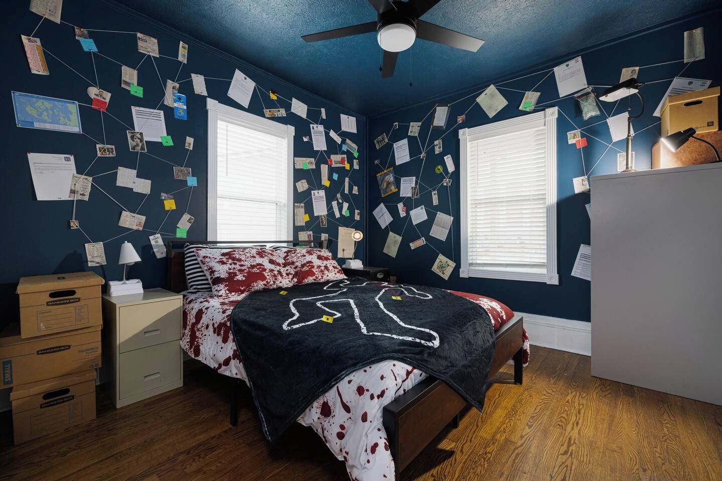 A bedroom with a bed, a nightstand, a dresser, a ceiling fan, and a window with blinds.