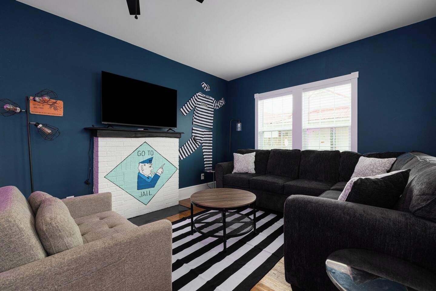 A living room with a dark blue wall, a fireplace, a sofa, a coffee table, and a television mounted on the wall.