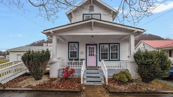 A two-story house with a front porch, a pink door, and a mailbox.