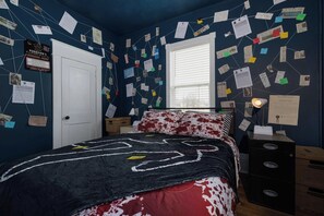 Un dormitorio con cama, escritorio y una pared llena de papeles y notas.