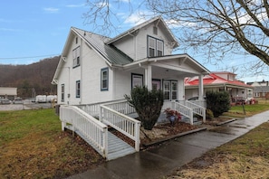 A two-story house with a front porch, a staircase, and a small garden area.