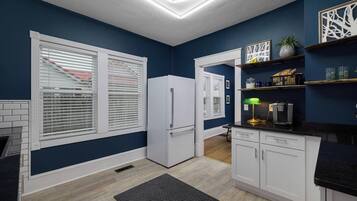 A kitchen with white cabinets, a refrigerator, a coffee maker, and a black countertop.