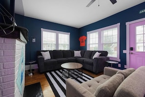 A living room with a sectional sofa, a round coffee table, and a striped rug. - Jailhouse Rock Retreat {Arcade+Secret Passage} (Elizabethton)