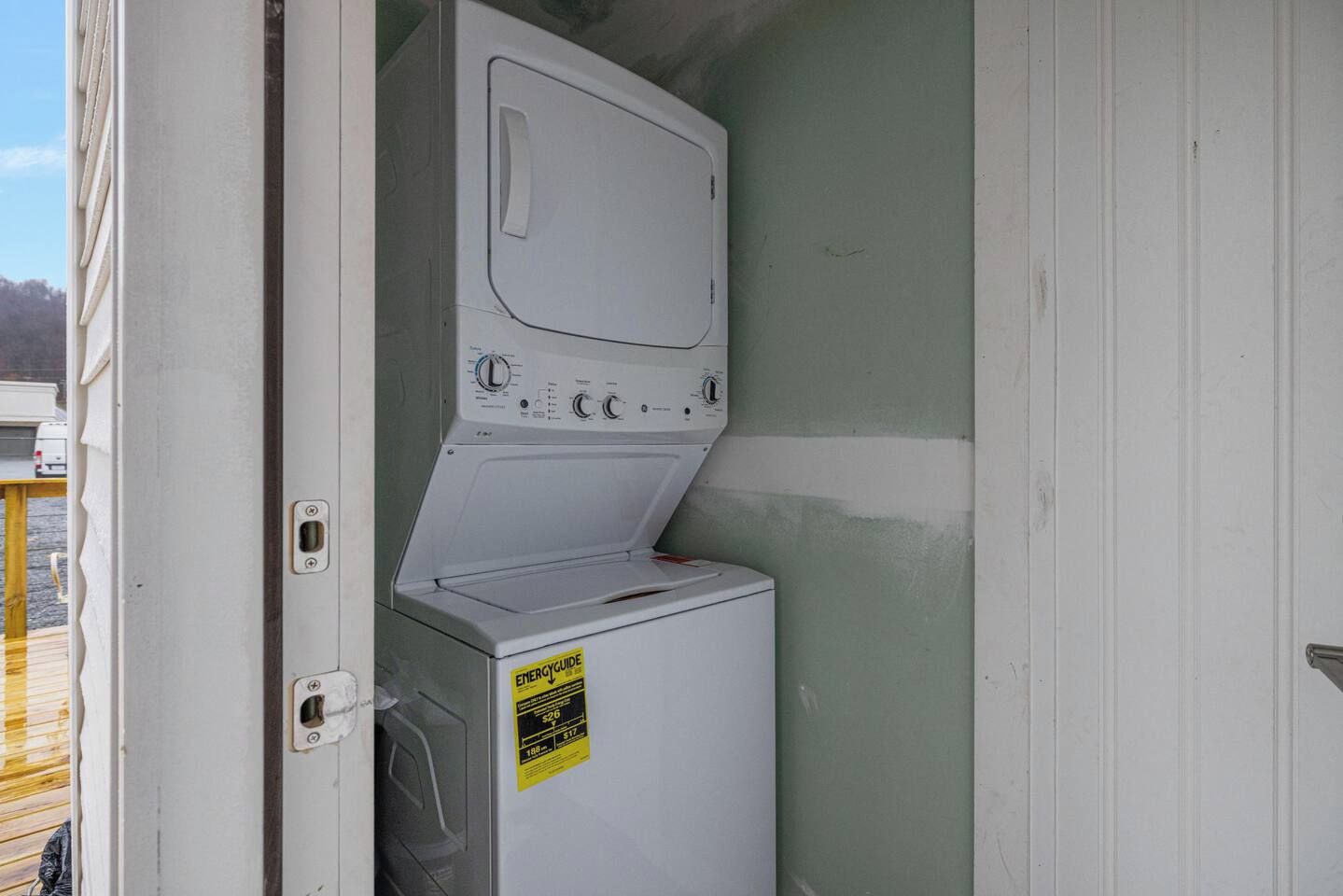 Een praktische wasruimte met een wasmachine en droger, een deur en een klein raam.