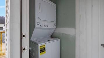 Een praktische wasruimte met een wasmachine en droger, een deur en een klein raam.