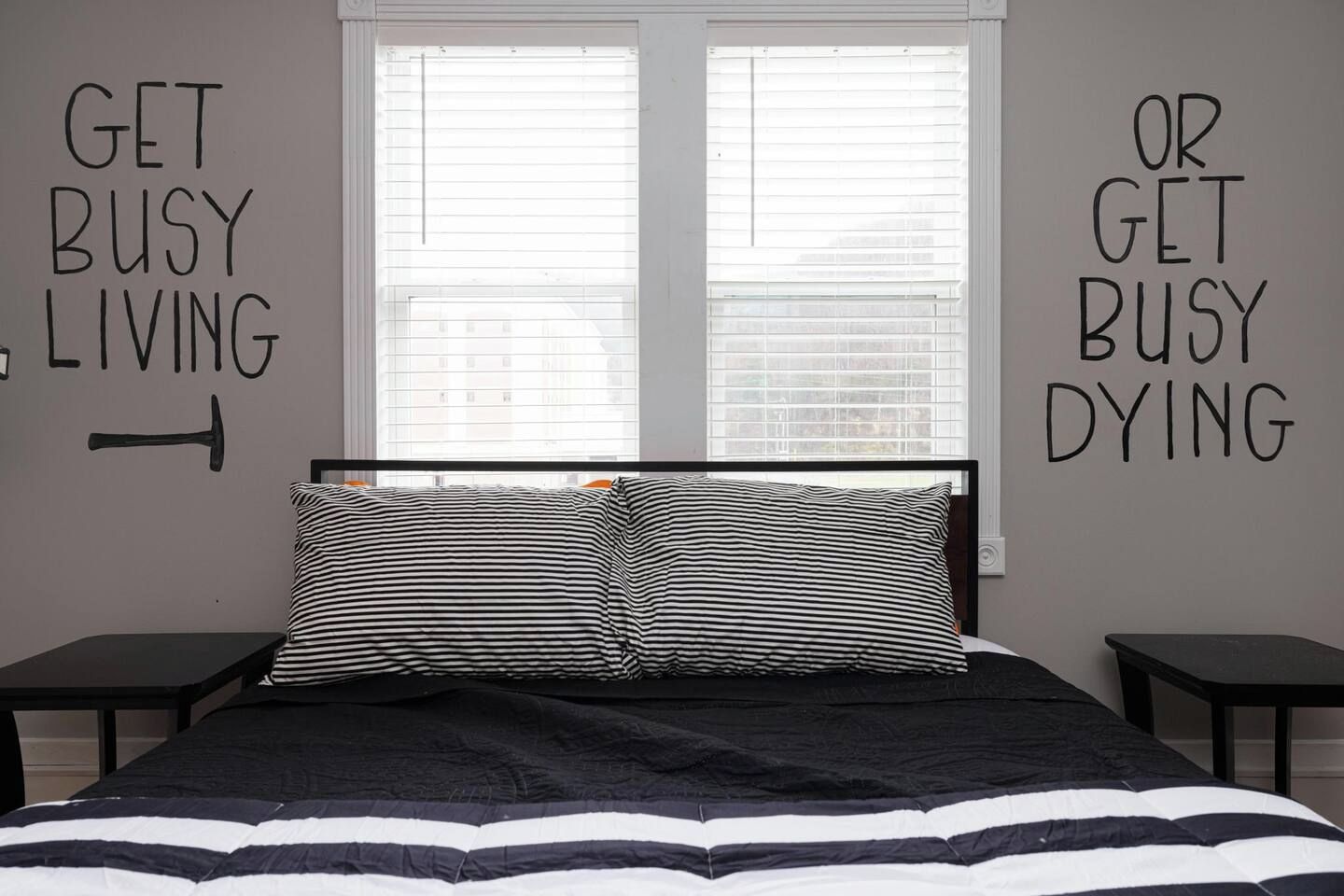 Een slaapkamer met een bed, twee nachtkastjes en een raam met jaloezieën.