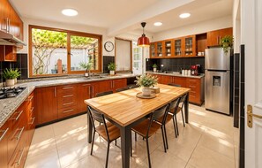 Una cocina moderna con armarios de madera, un refrigerador de acero inoxidable y una mesa de comedor con sillas.