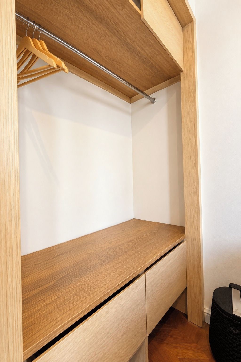 Un armario de madera con una barra para colgar y un estante plano.