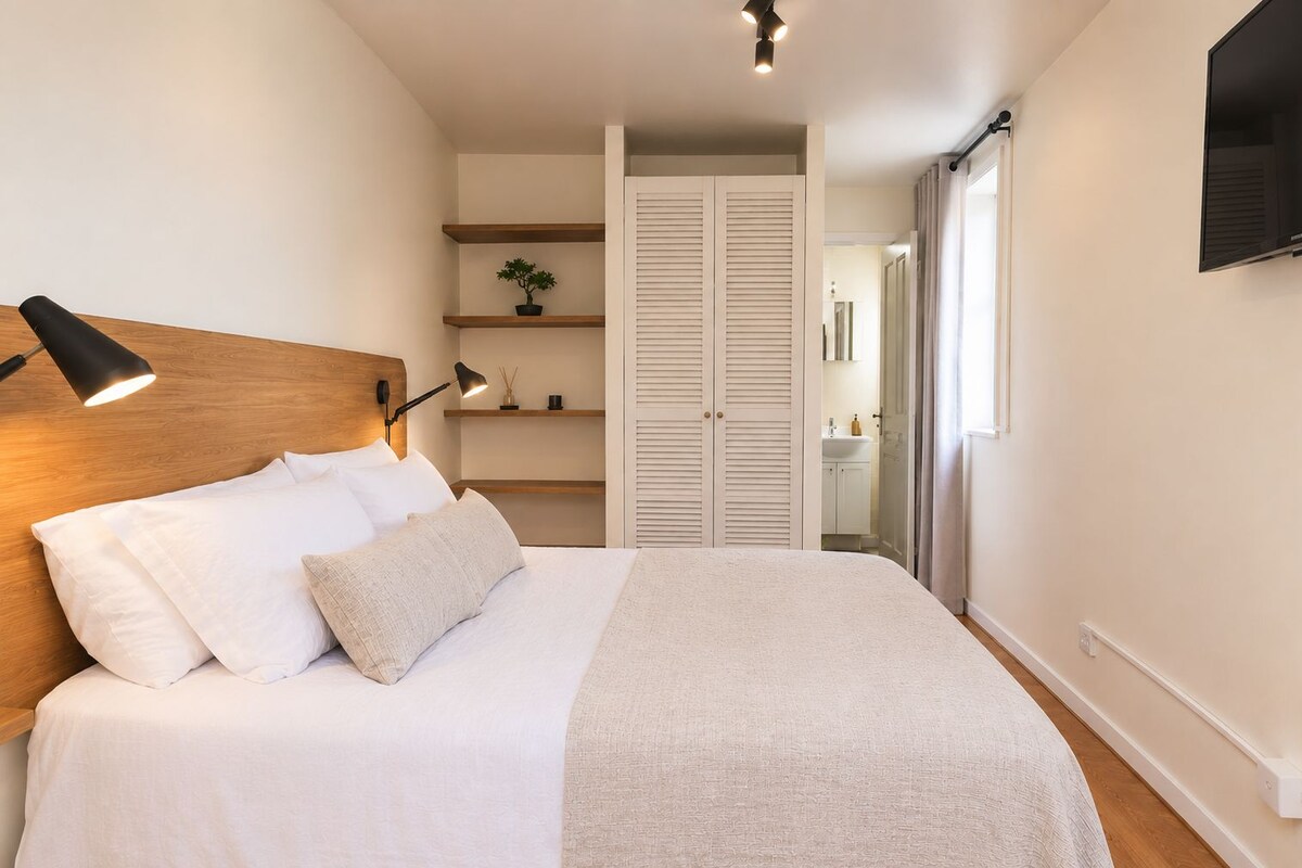 Une chambre à coucher avec un lit, une lampe de chevet et un téléviseur fixé au mur.