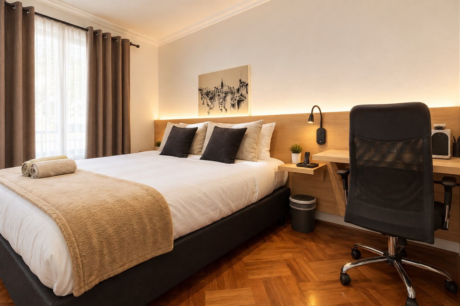 Habitación de hotel con cama, mesita de noche, lámpara, silla y una obra de arte en la pared.