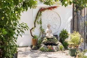 A serene garden with a Buddha statue, a circular wall, and various plants. - Yogi Hostels (Santiago)