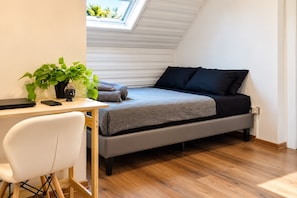 A compact bedroom with a bed, a desk, and a chair.