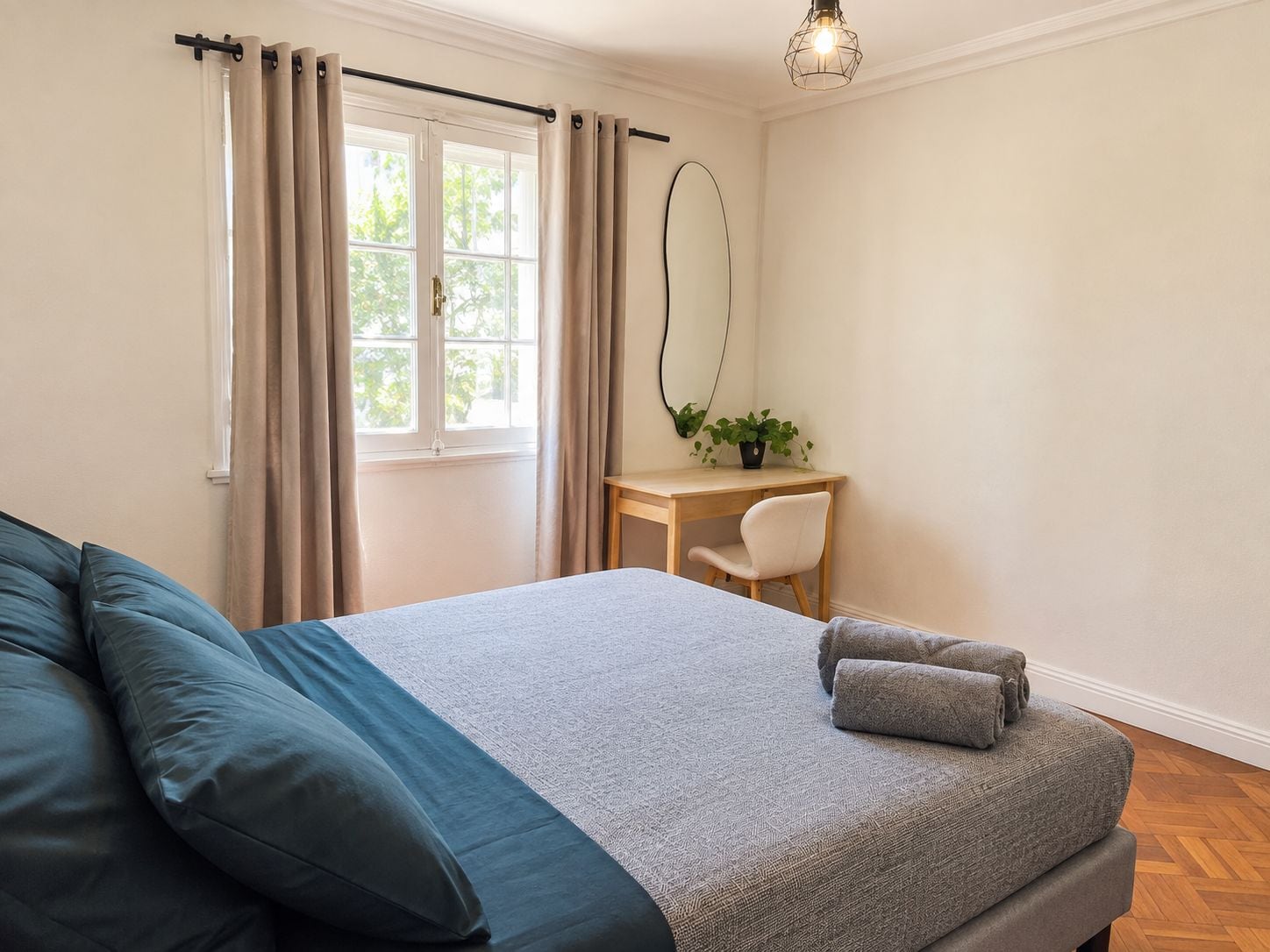 A bedroom with a bed, a desk, and a chair.
