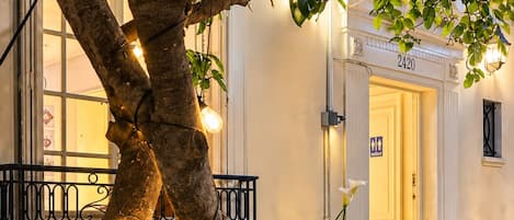 An outdoor seating area with a tree, string lights, and a building entrance.