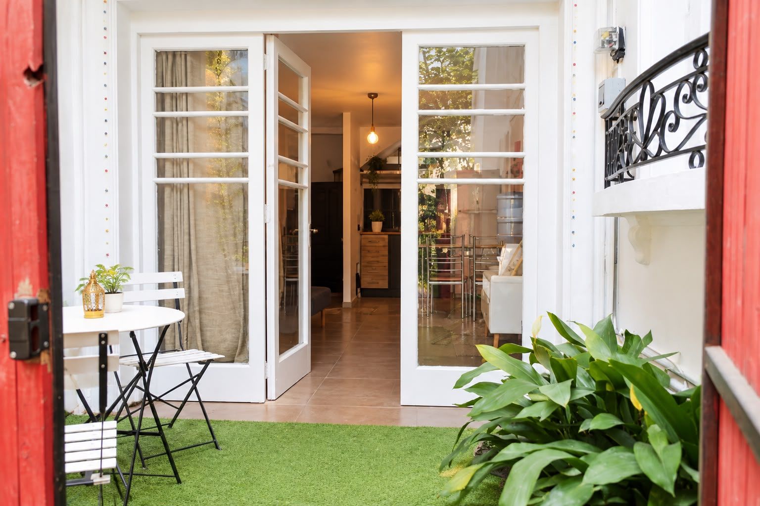 A doorway leading to a dining area with a table and chairs, a hanging light fixture, and a view into the interior.