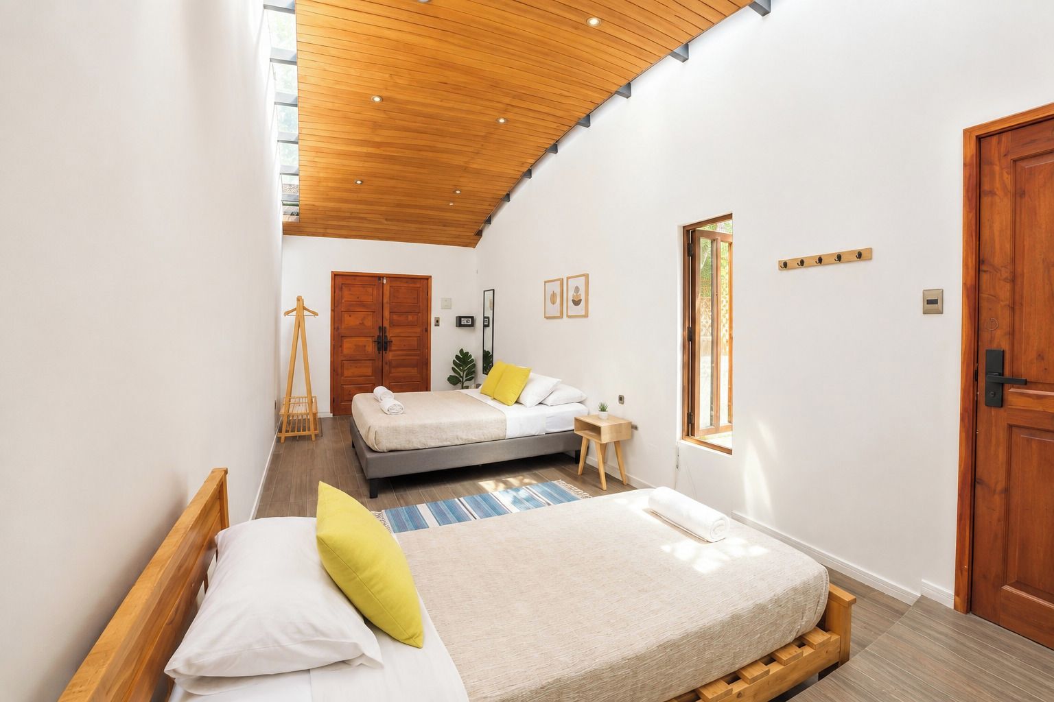 A bedroom with a bed, bedside tables, a wardrobe, a window, and a wooden ceiling.