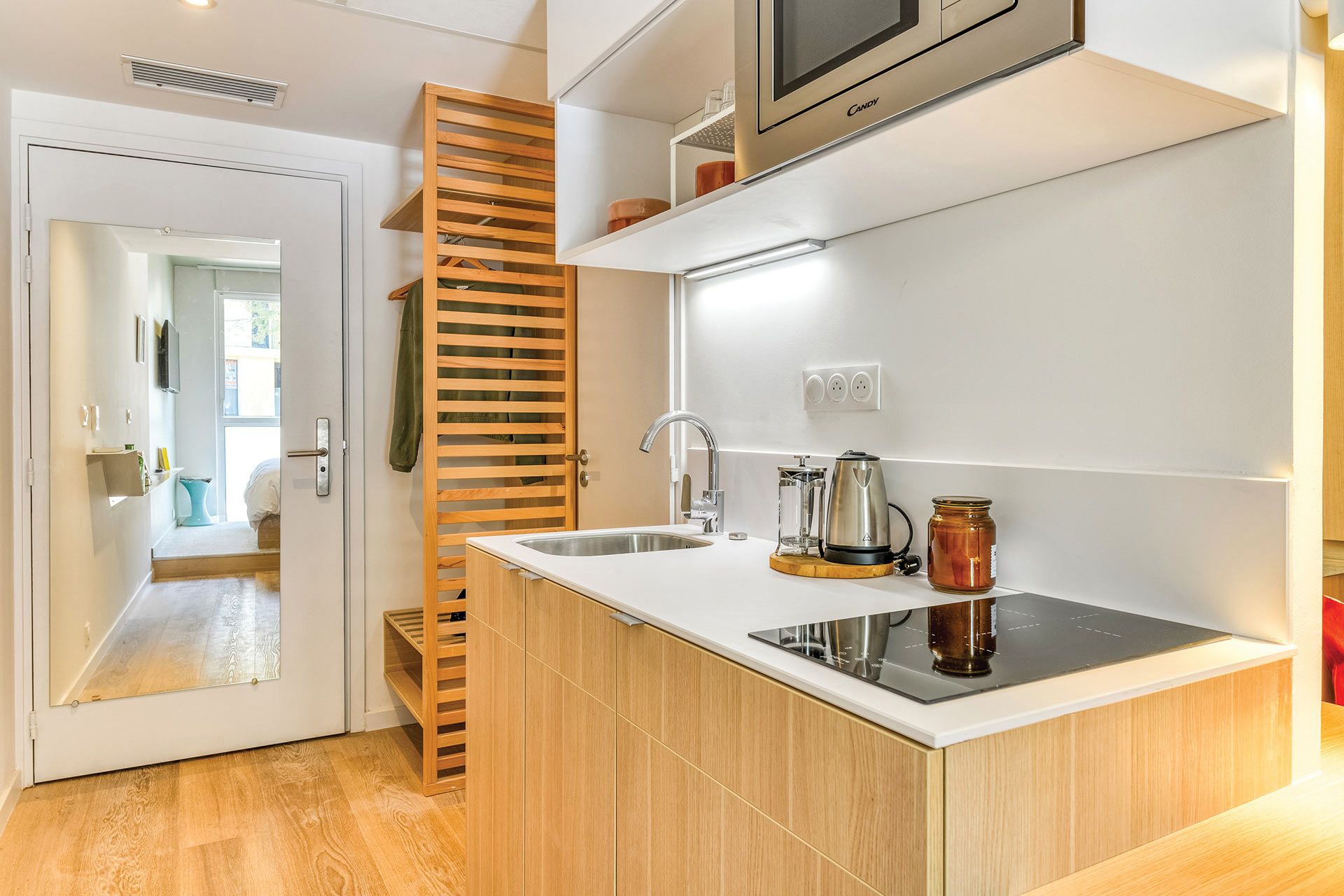 A modern kitchen with a built-in stove, a sink, and a wooden rack.