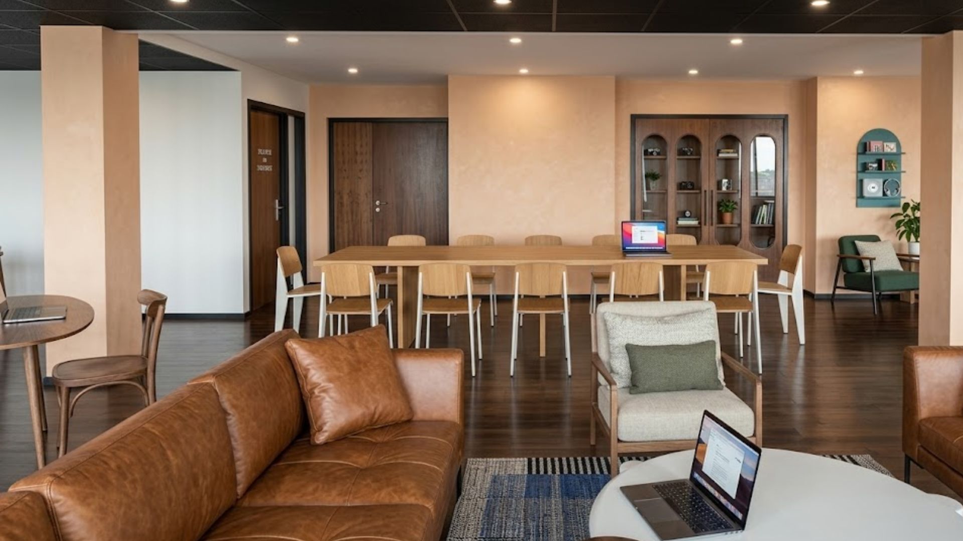 A modern lounge area with a leather sofa, a round table, and a long dining table with chairs.