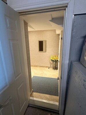 A doorway leading to a room with a small window and a doormat. - One bedroom basement apartment (Vaughan)