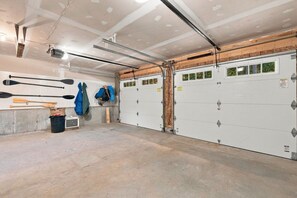 Eine Garage mit zwei weißen Garagentüren, einer Werkzeugtafel mit Schlägern und einem Baseballschläger sowie einem Betonboden.