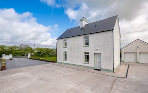 A two-story house with a grey roof, a front door, and a garage. - Newly Renovated Farmhouse (KY)