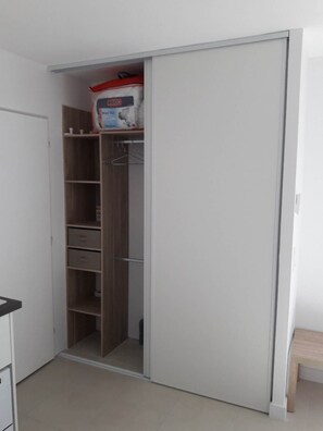 A room with a white wardrobe, a wooden bench, and a tiled floor. - 4-Star Furnished Studio (West-Facing) (JONZAC)