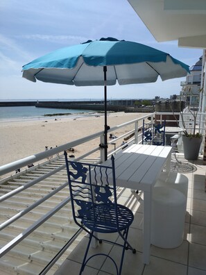 Un balcón con mesa y sillas, con vista a una playa y un muelle.