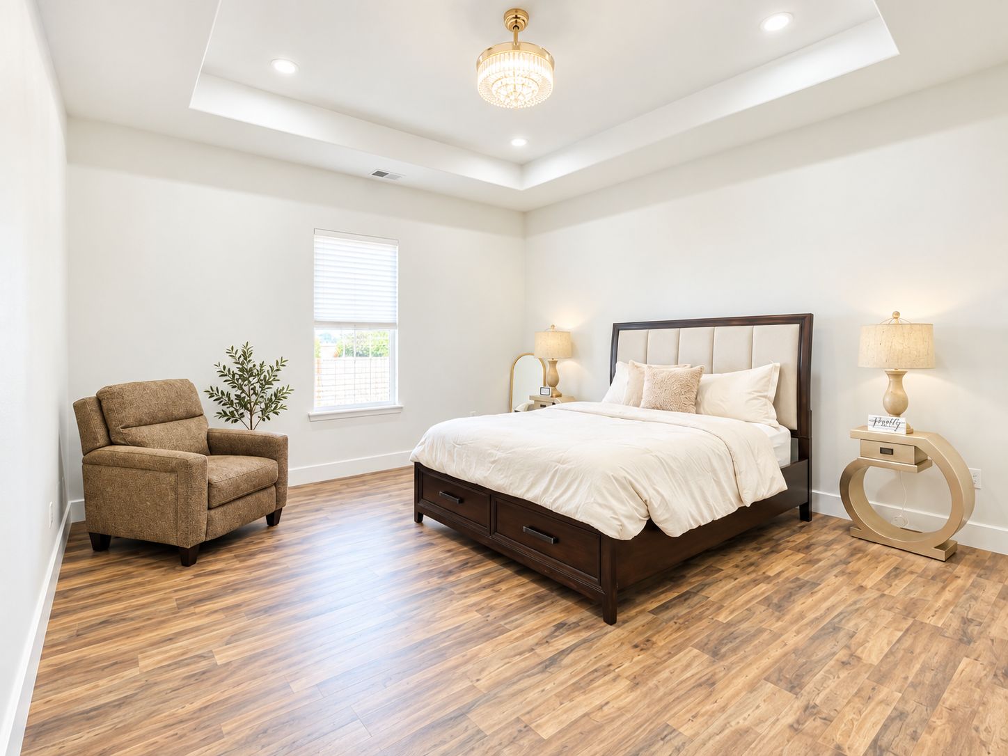 A bedroom with a large bed, a chair, a bedside table, a lamp, and a window.