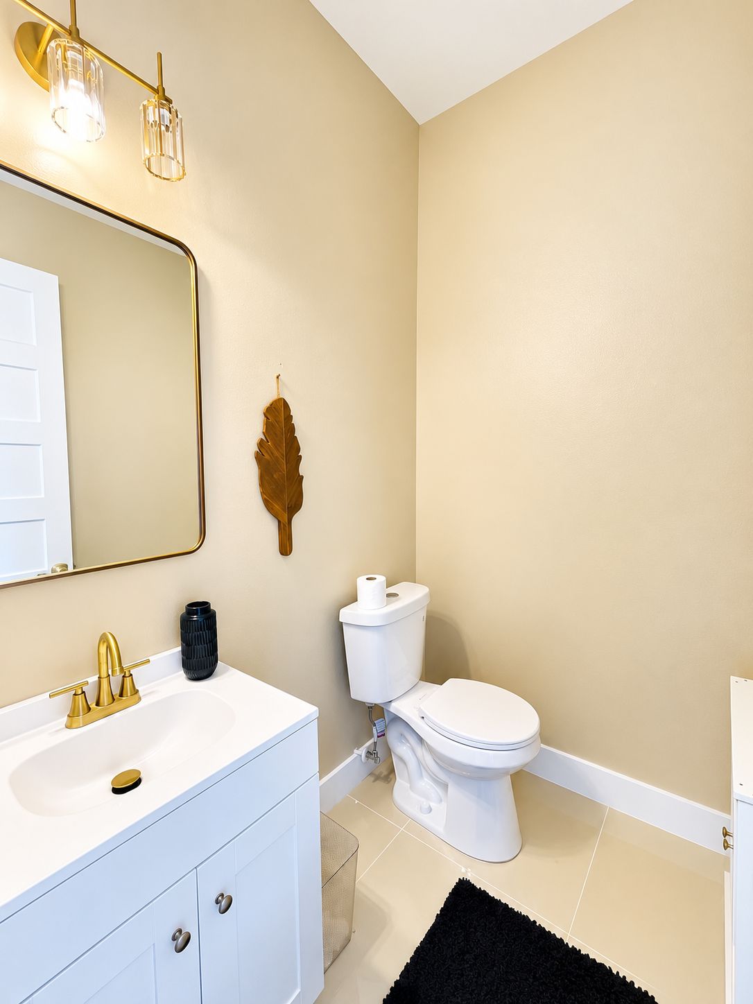 A bathroom with a white sink, gold faucet, and a toilet.