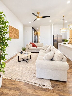 Una sala de estar moderna con un sofá modular, una mesa de centro redonda y un ventilador de techo.