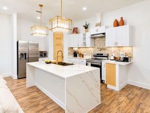 Una cocina moderna con una isla central, electrodomésticos de acero inoxidable y piso de madera.