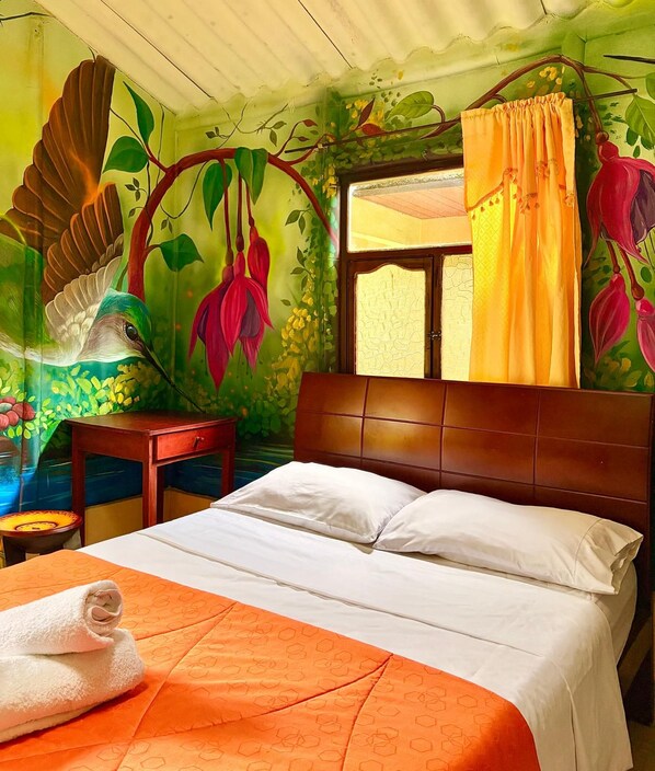 A room with a bed, a nightstand, a window with curtains, and a mural on the wall.