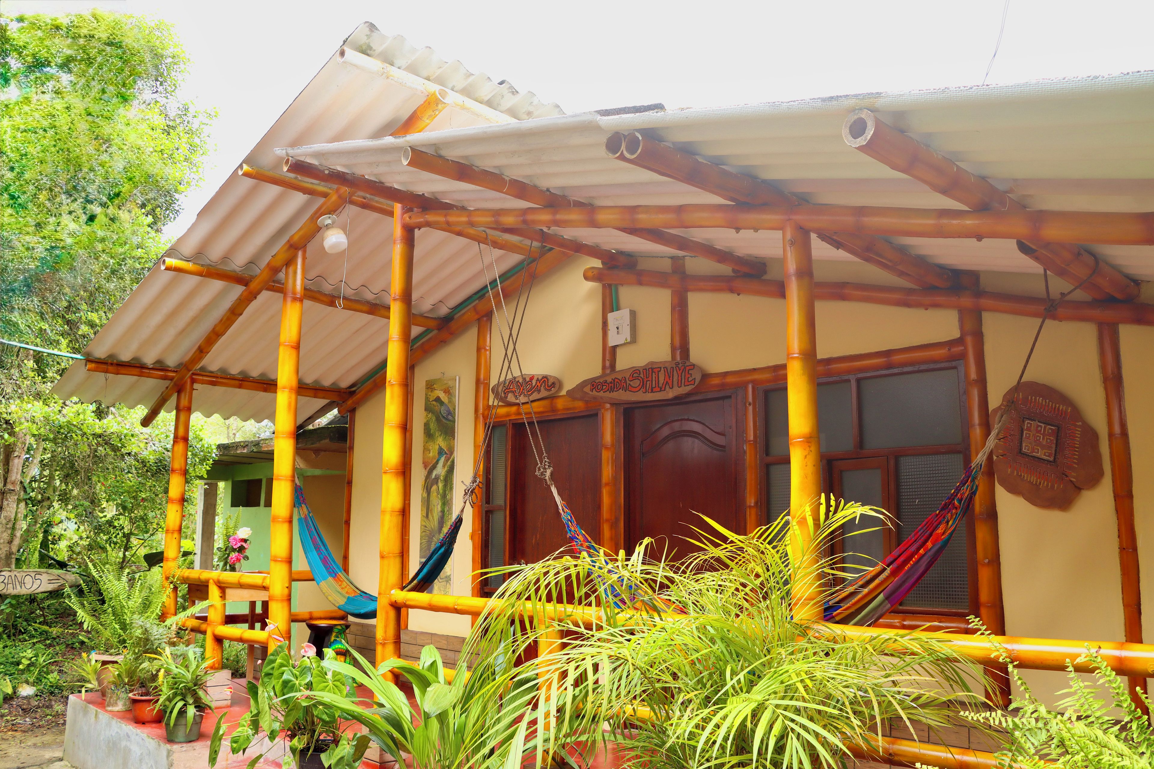 A house with a bamboo structure, a porch, and a door with a sign.