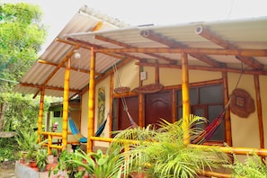 A house with a bamboo structure, a porch, and a door with a sign.