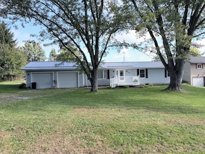 A single-story house with a garage, a porch, and a large tree in front. - Golf Course Getaway in Apple Valley – Fully upgraded 3BR Home w/ screened porch (Howard)