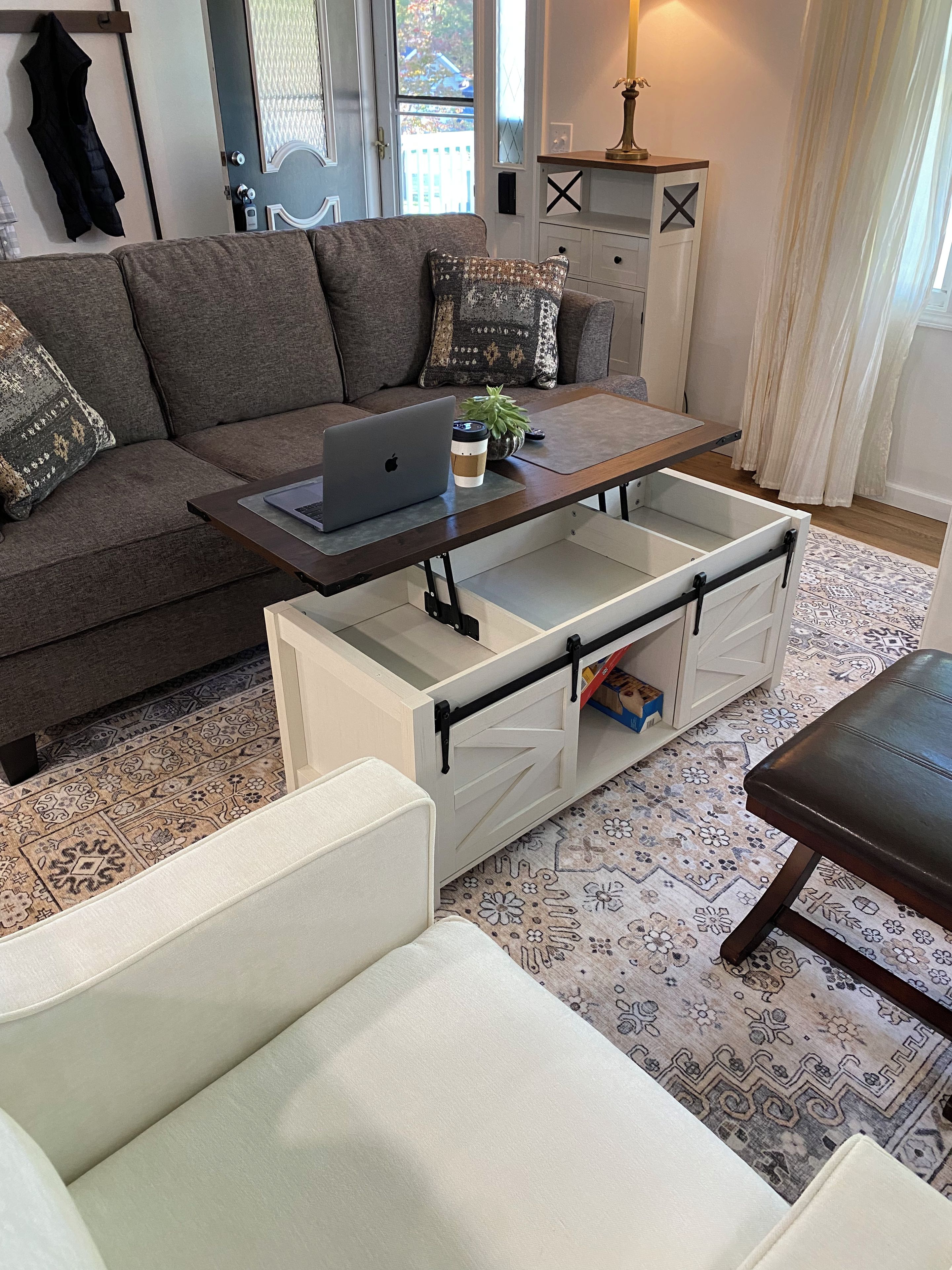 Uma sala de estar moderna com um sofá, uma mesa de centro com um laptop e uma planta decorativa.