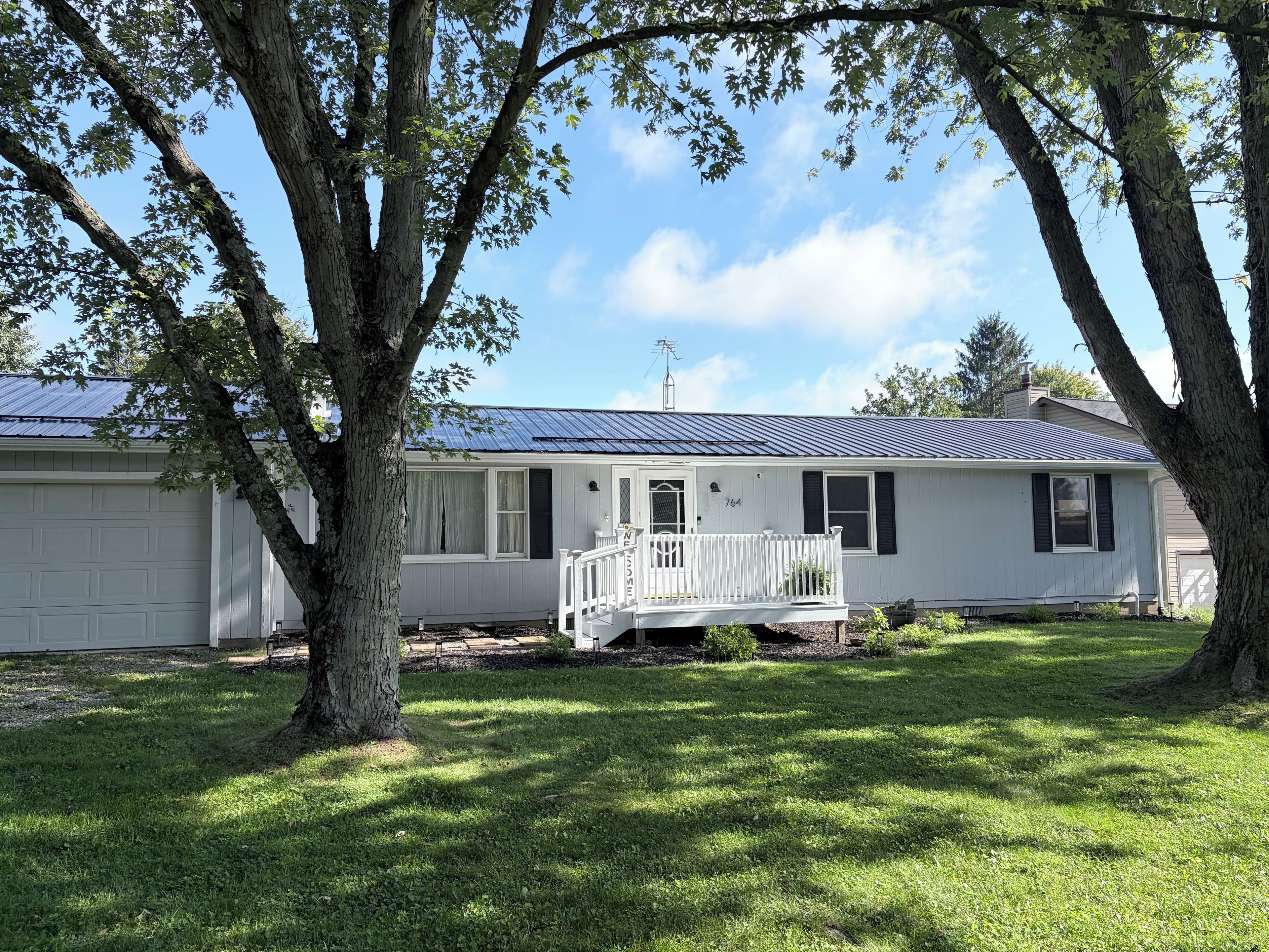 A single-story house with a porch, a garage, and a well-maintained lawn.