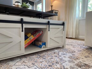 A kitchen counter with storage cabinets, a patterned rug, and a window with curtains.