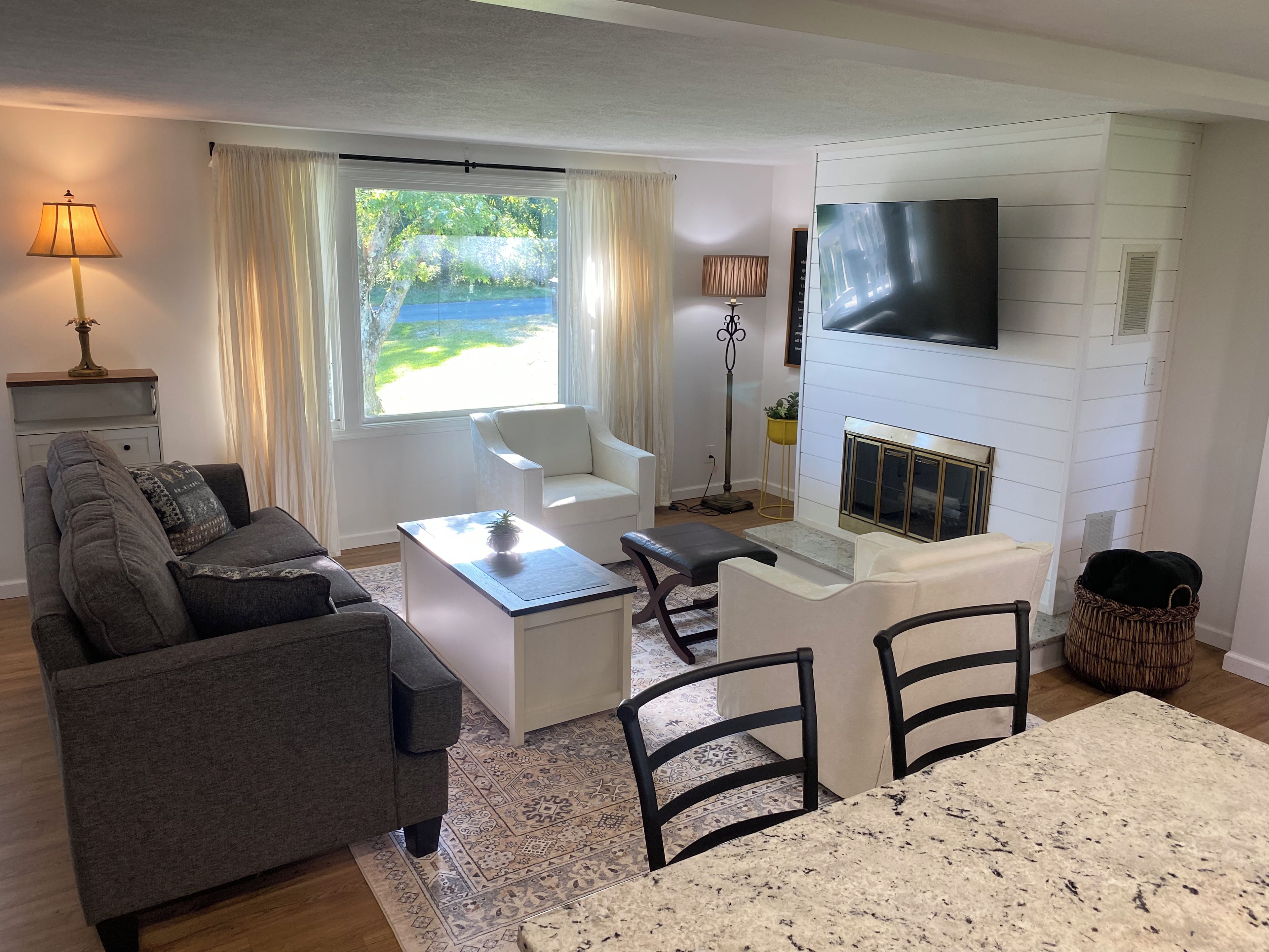 Un salon comprenant un canapé, une table basse et des fauteuils, une cheminée et un téléviseur fixé au mur.