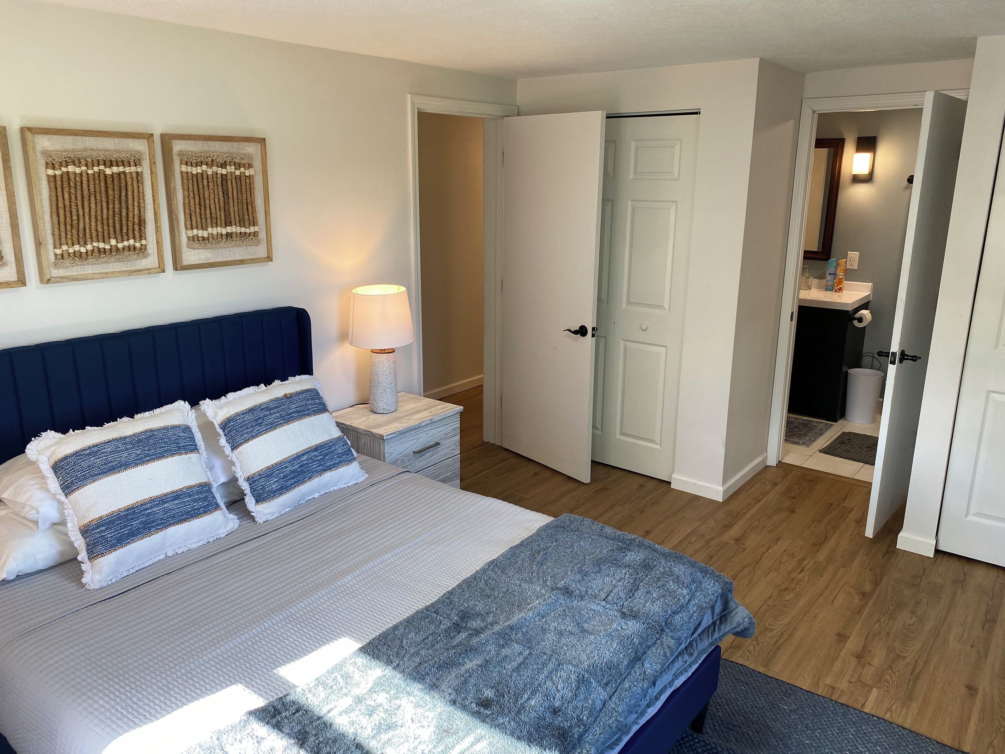 Une chambre à coucher comprenant un lit, des lampes de chevet, une porte donnant sur une salle de bain et un couloir.