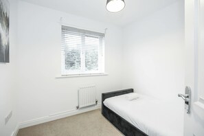 A bedroom with a single bed, a radiator, a window with blinds, and a light fixture. - Hot Tub,Parking,Nr Edinburgh,Contractor Stay,4BED (East Lothian)