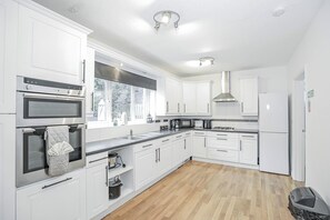 Una cocina moderna con armarios blancos, electrodomésticos de acero inoxidable y piso de madera.